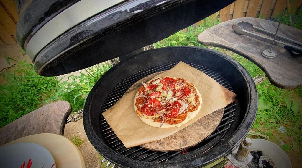 de pizza, met saus, en toppings op de gril